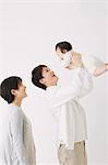 Young adult couple and son. Father lifting his son and smiling