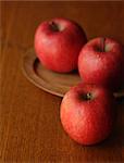 Three red apples on a wooden table