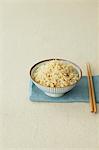 Cup of brown rice and chopsticks on a table