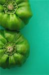 Two green peppers on green background