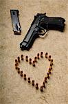 A gun and ammunition formed into a heart.