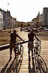 Two men walking with bicycles against the light, Denmark.