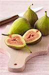 Close-up of Fresh Figs, One Cut in Half on Wooden Cutting Board on Pink Background