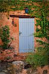 Old blue entrance door in orange wall, Provence, France