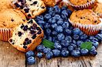 Homemade muffins with fresh blueberries on wooden table