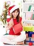 Beautiful Asian female peeking inside Christmas gift, indoor / inside house