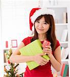 Asian Christmas woman with gift, indoor / inside house.