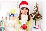 Asian female in santa hat giving a Christmas gift