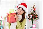 Happy Asian woman in santa hat showing her Christmas gift