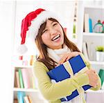 Asian female holding her Christmas gift smiling happily, indoor/inside house.