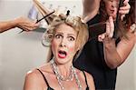 Hair stylists working around surprised blond woman