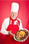 Handsome, experienced chef holding stuffed turkey dinner.  Red background.