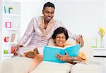 Mature 50s Indian woman reading a book with her son at home