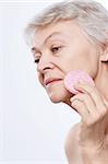 Elderly woman wipes the skin on a white background