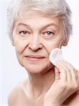 Elderly woman wipes the skin on a white background
