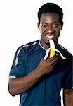 Young fit guy eating banana. Posing in front of camera