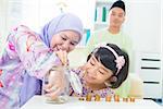 Southeast Asian family saving money at home. Muslim family living lifestyle.