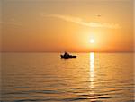 Above the sea, the sky lit up the setting sun. Its rays are colored highlights on the waves of the sea. In the sea to the black silhouette of a ship.