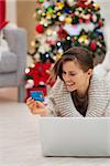 Happy woman near Christmas tree shopping online