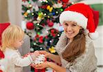 Happy mother giving baby Christmas cookies