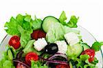 Mixed salad in a glass bowl close up. White isolated