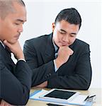 Southeast Asian business people discussing, sitting in office.