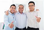 Thumbs up Southeast Asian businessmen standing in office
