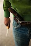 Close-up of Young Man holding Knife with Handgun tucked into Waistband of Blue Jeans, Mannheim. Baden-Wurttemberg, Germany