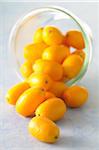 Close-up of Bowl of Kumquats Spilling on Blue Background, Studio Shot