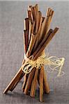 Close-up of Cinnamon Sticks tied with Raffia on Grey Background, Studio Shot