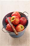 Overhead View of Colander filled with Red Apples and a Knife on Beige Background, Studio Shot