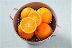 Overhead View of Oranges in Colander on Blue Background, Studio Shot