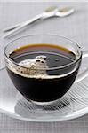 Close-up of Black Coffee in Glass Cup and Saucer on Grey Background, Studio Shot