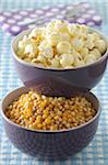 Bowls of Corn Kernels and Popcorn on Blue Gingham Background, Studio Shot