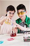 Boy and Girl wearing Safety Glasses Pouring substance into Beaker, Mannheim, Baden-Wurttemberg, Germany