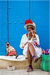 Woman Smoking Cigar and Sitting on Curb with Cat Wearing Costume, Old Havana, Havana, Cuba