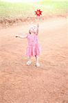Girl playing with pinwheel on dirt road