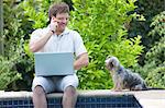 Man using cell phone and laptop outdoors