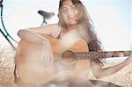 Woman playing guitar in tall grass