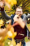 Man playing in autumn leaves