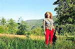 Woman holding guitar in grassy field