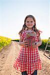 Girl carrying apples on dirt road