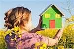 Girl holding model house in field