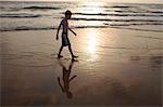 Boy walking in waves on beach