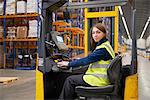 Worker operating forklift in warehouse