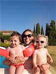 Mother holding daughters by pool