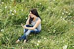 Woman listening to headphones in grass