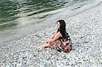 Woman sitting on rocky beach