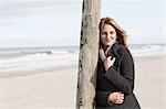 Woman leaning on pole on beach