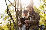 Couple using tablet computer in forest